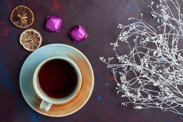 Night Bliss Infusion Tea served in a ceramic cup with dried citrus slices and chocolates on a dark background, creating a calming evening ambiance.